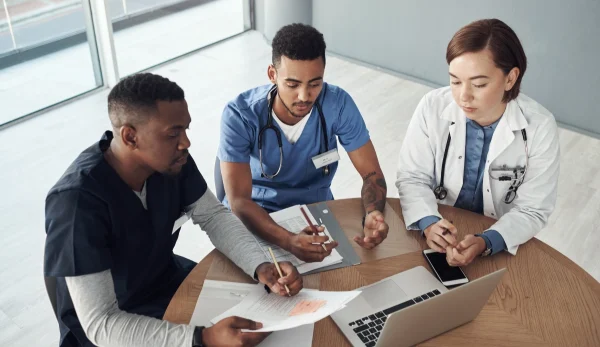 Three nursing students sitting at table having a discussion. UConn Online Nursing BS-DNP Program.
