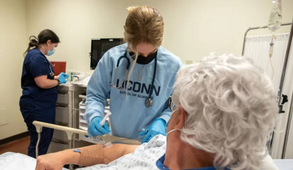 UConn Nursing student administering to patient. UConn Online Nursing Graduate Degree Programs.