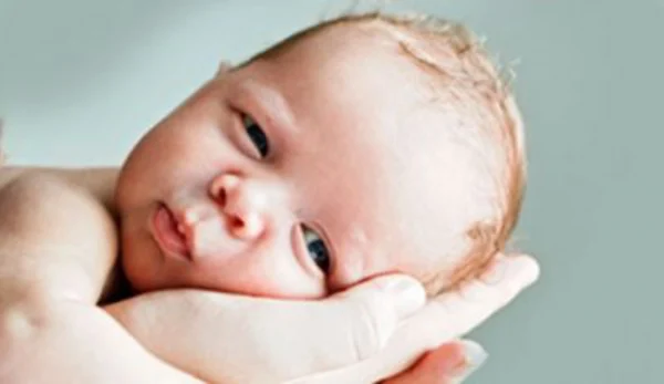 Close up of infant with adult hand supporting its head. UConn Online Nursing Graduate Programs